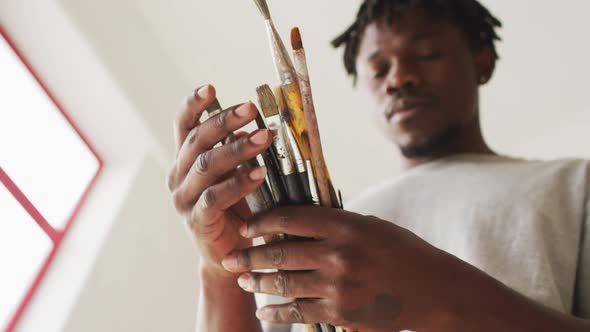 African american male painter choosing brushes in artist studio