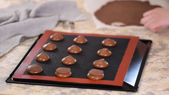 Pastry chef decorates raw profiteroles with chocolate shortcrust pastry