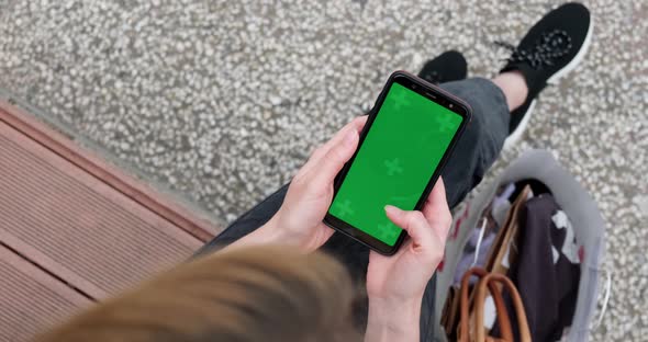 Smartphone green screen mockup, top view of woman using phone.