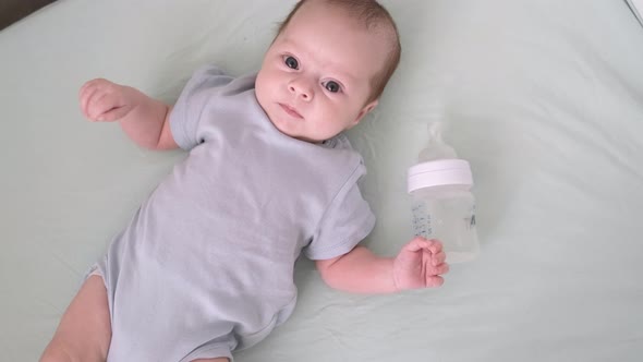 Little Boy Child with Milk Baby Bottle in Crib at Home Portrait Infant Satiated Baby Who Just Drank