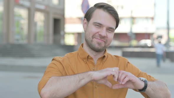 Loving Young Man showing Heart Shape by Hands Outdoor