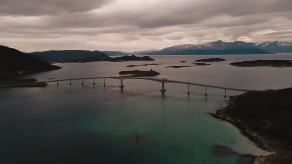 Epic pink sky during arctic sunset as drone shows Sommaroy bridge over the ocean, Norway