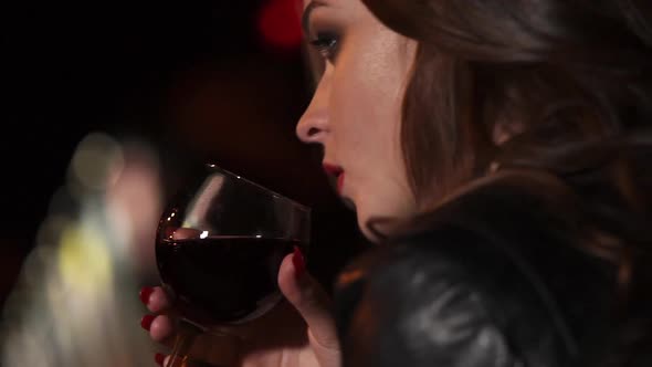 }Young and Beautiful Lady Drinking Wine From a Glass in the Evening on the Street