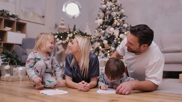 Happy Parents with Children Write Letters To Santa Claus Before Christmas