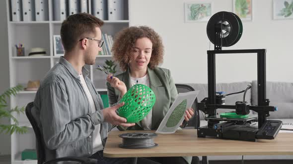 Creative Man and Woman Use Modern Electronic Technology and Study 3 Model Made on 3D Printer Sits at