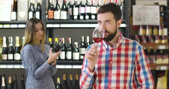 Portrait of Young Professional Sommelier Smelling Expensive Red Wine in Glass and Showing Thumb Up