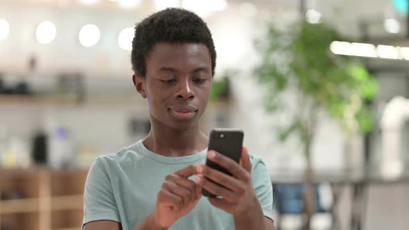 Young African Man Using Smartphone Text Messaging