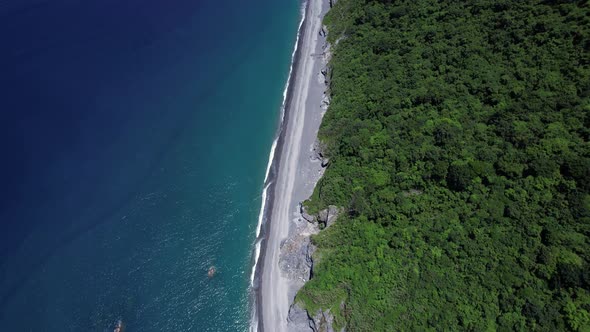 Tropical beach covered in fallen boulders from gradual cliff-side erosion on the Eastern coast of Ta