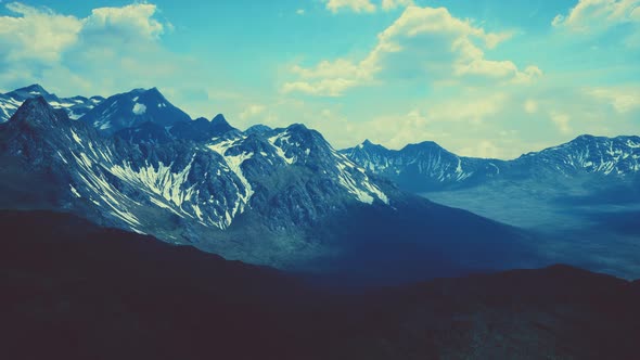 Aerial Over Valley With Snow Capped Mountains In Distance