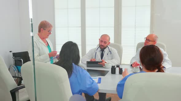 Expert Elderly Woman Doctor Discussing with Medical Staff