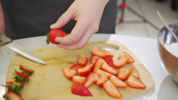 Strawberries are Cut Into Pieces on a Wooden Cutting Board to Decorate Desserts