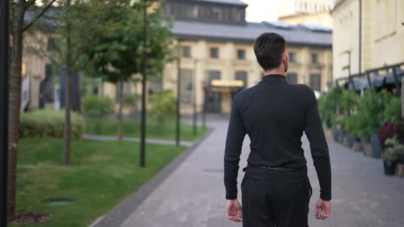 Back View Young Confident Man Strolling on City Street in the Morning