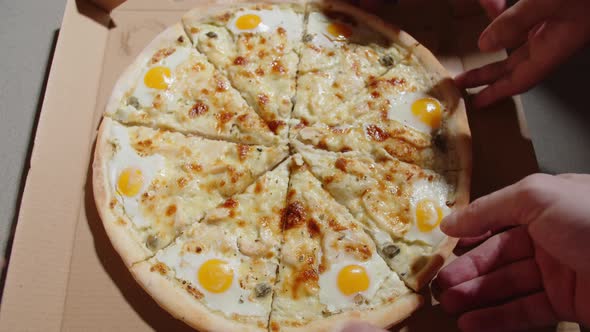 Human Hands Take Slices of Fresh Pizza From an Open Box