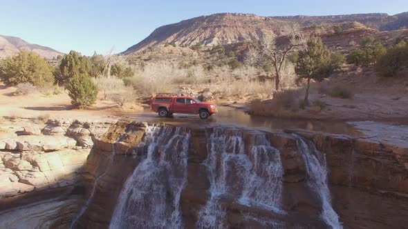 Aerial view of truck driving over waterfall in the Utah desert