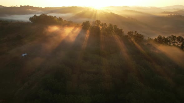 Aerial view of sunrise with fog above mountains. Golden hour and amazing sun rays. Nan, Thailand