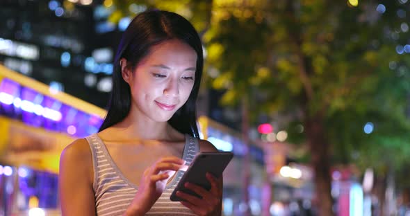 Woman using mobile phone in city at night 