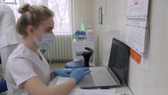 Dentist Assistant Working on Laptop Computer in Dental Office