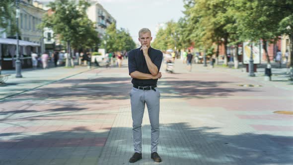 Time Lapse of Attractive Blond Guy Standing Outdoors in Busy Street with Pensive Expression and