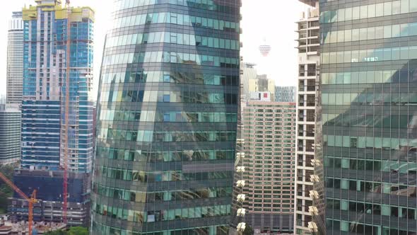 Pedestal up aerial shot capturing shimmering and glittering glass windows of office towers, reveals