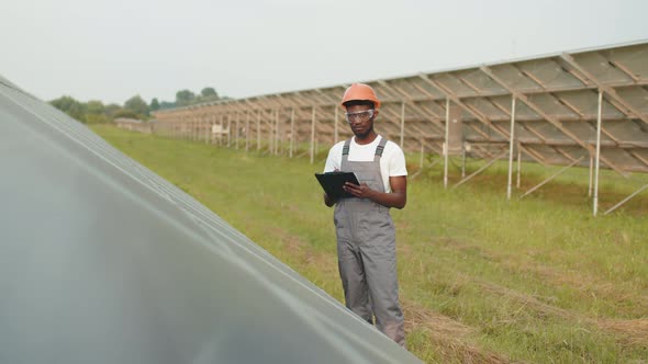 African American Engineer Writing Notes on Clipboard During Inspection of Solar