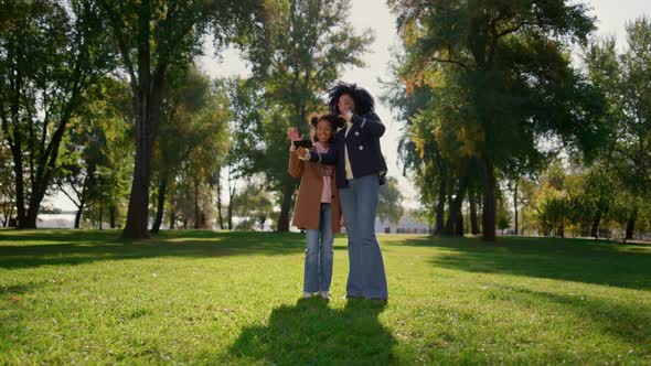 Happy Mother Making Online Call with Cute Smiling Daughter Standing in Park