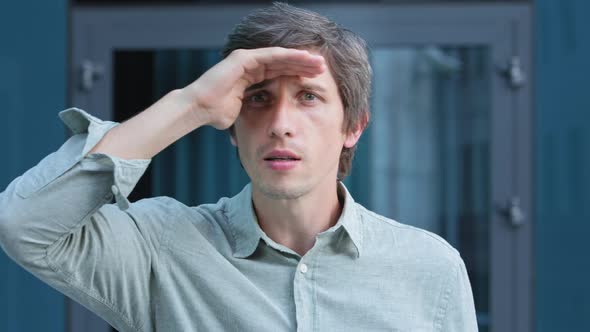 Headshot Portrait of Man Looking Suspicious Gazes Intently Peers Into Distance Covers Face From Sun