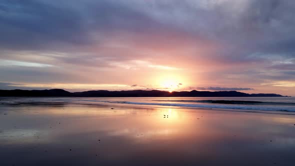 Scenic Sunset With Ocean Waves Splashing On The Shore At Spirits Bay, New Zealand - drone shot