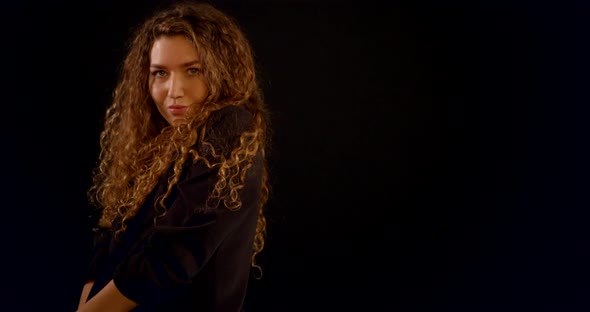 A Close-up Portrait of a Curly-haired Young Girl Who Is in the Studio on a Black Background, Wearing