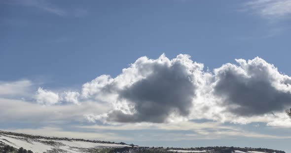 Time Lapse of Cloudscape Behind of the Mountains Top. Snow, Rocks, Cliffs and Deep Blue Sky. High