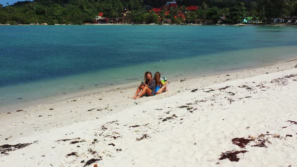 Young smiling girls on holiday in the sun on beach on summer white sandy and blue background 4K