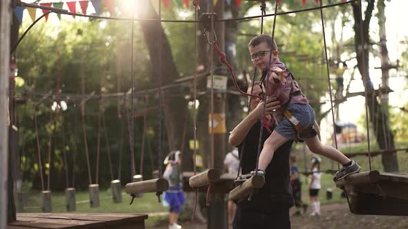 Father Supports a Son Walking on a Rope Bridge