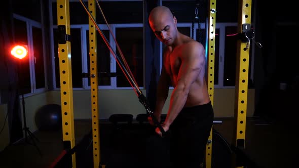 Male Bodybuilder Training with Resistance Bands for Triceps in the Gym