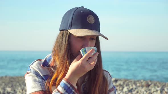 woman holds a teacup and thoughtfully looks deep into herself on the seashore.