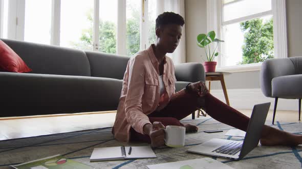 African american woman drinking coffee while working from home