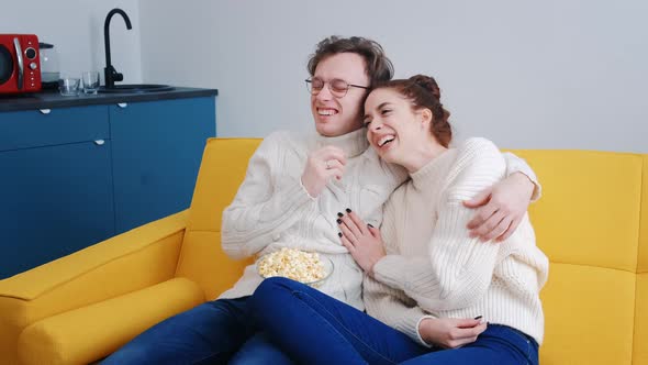 A Young Overjoyed Couple at Home Watching a Comedy Movie Laughing Loudly
