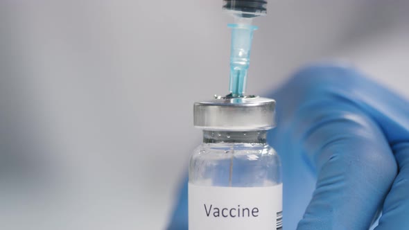 Gloved Hands Filling Syringe with Vaccine