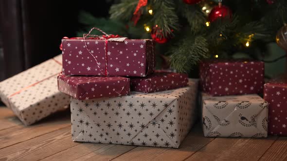 Christmas Beautiful Gift Boxes in a Stack of Presents Lie on the Wooden Floor Under the Tree