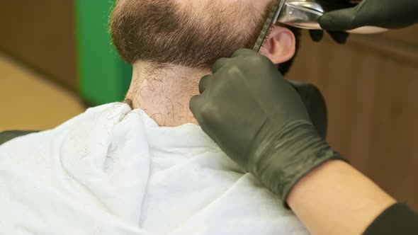 Stylist Hands Hold Plastic Comb and Trimmer Cutting Beard