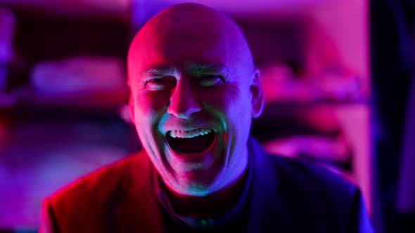 Crazy Man is Laughing in Nightclub Portrait in Neon Lights Mad Smile and Laugh