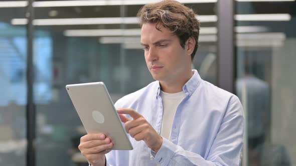 Portrait of Man Celebrating on Tablet in Office