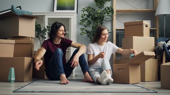 Young Woman Taking Things From Box and Talking with Boyfriend During Relocation