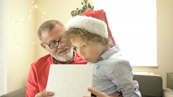 Grandfather Makes a Christmas Present for His Teenage Grandson. The Boy in the Santa Hat Is