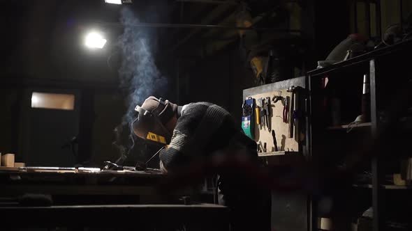 Worker Welds an Iron Pipe