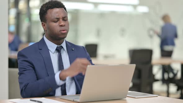 African Businessman Reacting to Loss While Using Laptop