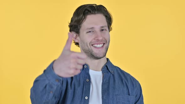 Thumbs Up By Positive Young Man on Yellow Background