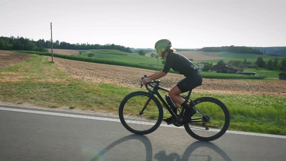 Female athlete standing while road cycling uphill