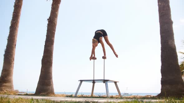 A Young Gymnastic Woman Working Out on the High Beams