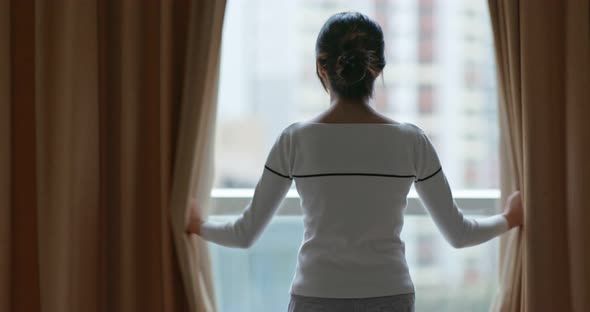 Woman open the curtain at home in the morning