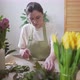 Professional Florist in a Green Apron Works with Flowers at the Table - VideoHive Item for Sale