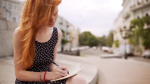 Young Cute Caucasian Redhead Girl Writing Notes Wearing Black Polka Dot Dress